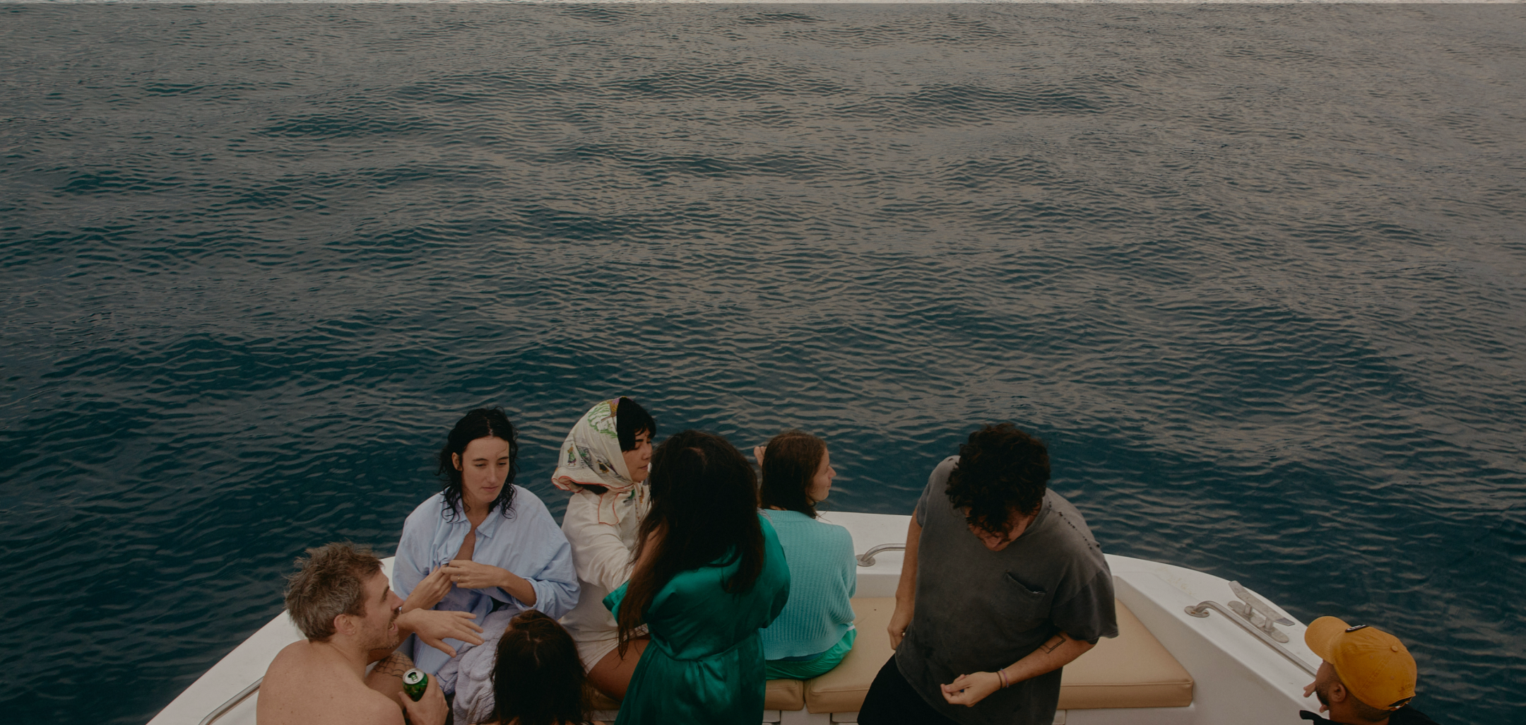 Group of friends on a boat surrounded by dark calm water.