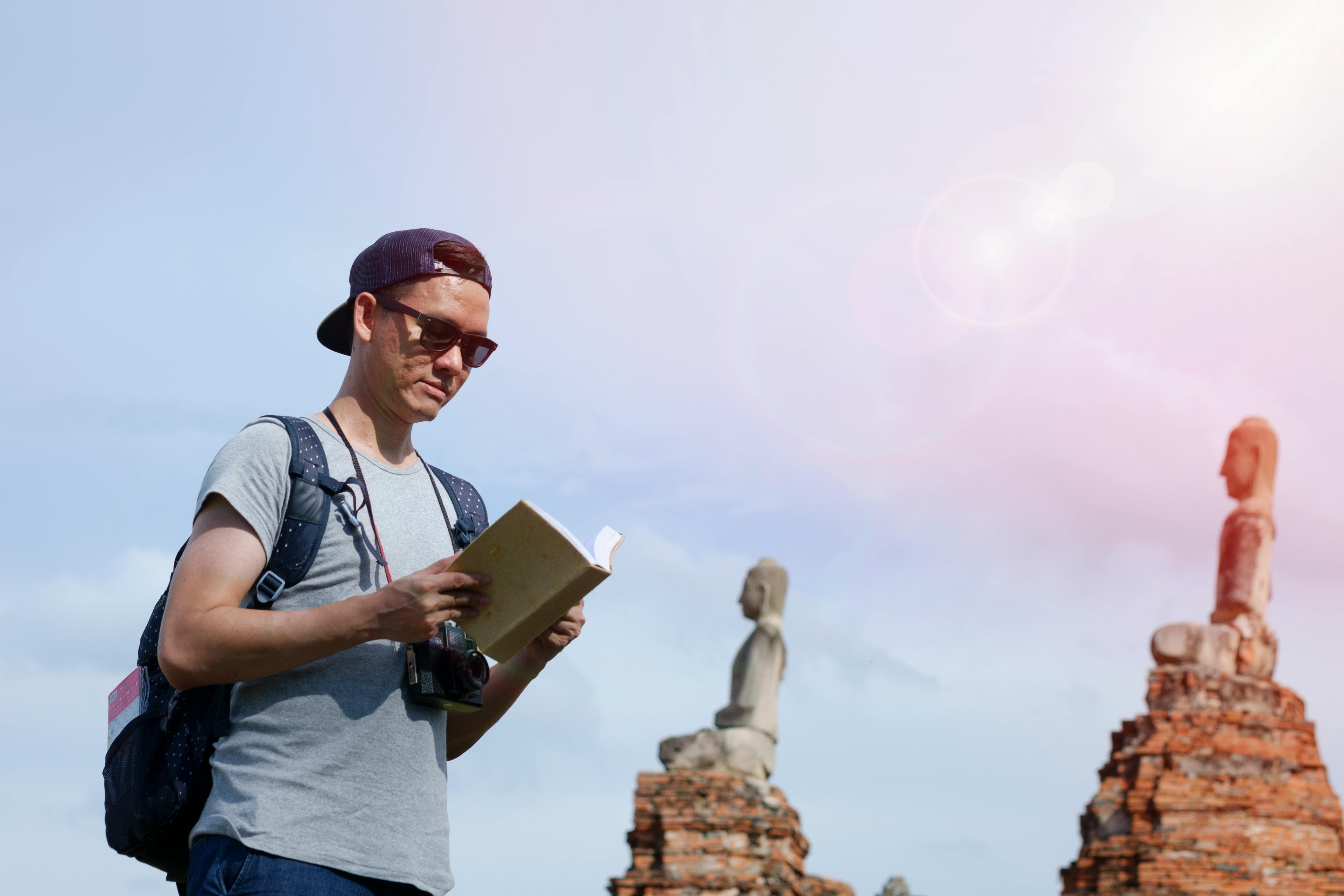 Man reading a book in front of a monument